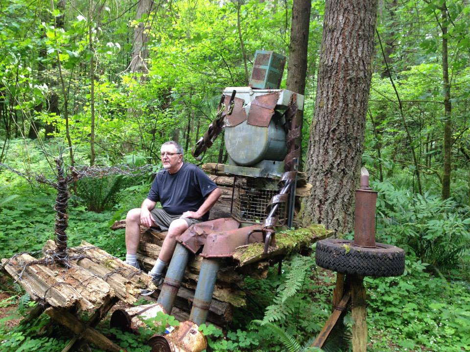 Second-hand Sid sits with Guerrilla Man sculpture in the woods